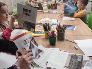 Dzieci siedzą przy stole i wykonują własne prace plastyczne.