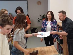 Dyrektor muzeum i bibliotekarka wręczają uczestnikom dyplomy.