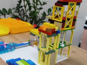 Na obrazku znajduje się makieta z wieżą zbudowaną z klocków LEGO.