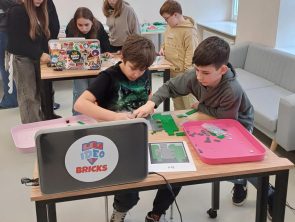 Uczestnicy warsztatów z LEGO budują makietę dworku Złotnickiego.