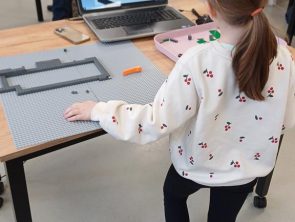Uczestnicy warsztatów z LEGO budują makietę dworku Złotnickiego.