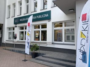 Dwie flagi z napisem Łódzkie przed wejściem do budynku biblioteki.