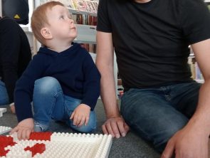 Opiekun wraz z dzieckiem buduje makietę z klocków LEGO.
