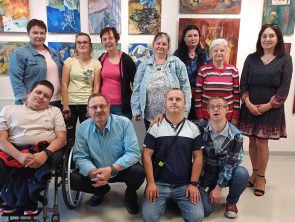 Marzena Sroczyńska z uczestnikami wernisażu na tle swoich obrazów
