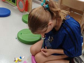 Dziewczynka buduje z klocków lego pięknego kwiatka