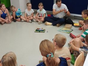 Pan razem z dziećmi budują z klocków lego gdzie tematem był Czarnoksiężnik z Krainy Oz