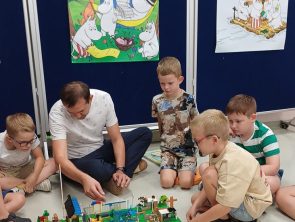 Pan razem z dziećmi budują z klocków lego gdzie tematem był Czarnoksiężnik z Krainy Oz