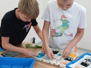 Chłopcy wybierają części do budowy robota z pojemnika