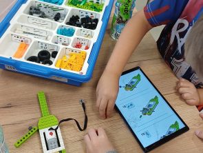 dzieci budują model pojazdu według instrukcji na tablecie