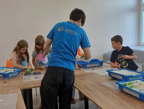 Dzieci przy stołach budują modele pojazdów