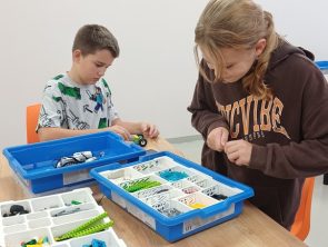 Uczestnicy na zajęciach wybierają klocki do budowy robota