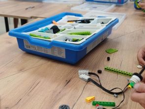 Dzieci przy stołach budują modele pojazdów