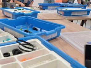 Dzieci przy stołach budują modele pojazdów