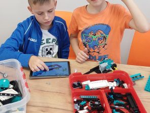 Chłopcy przy pomocy tableta sterują robotem