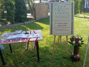 Po lewej stronie stolik z kroniką i okolicznościową pieczęcią Narodowego Czytania 2025, obok sztaluga z plakatem Jan Kochanowski. Poezje