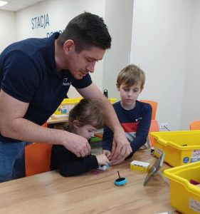 Pan pomaga dziecku przy budowie robota