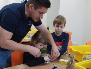 Pan pomaga dziecku przy budowie robota