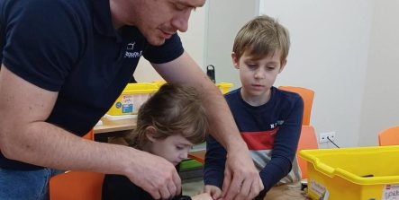 Pan pomaga dziecku przy budowie robota