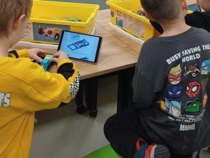 Dzieci przy pomocy tableta składają robota