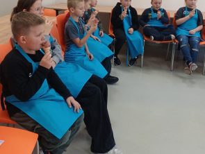 Dzieci siedzą na krzesłach i jedzą lody sorbetowe