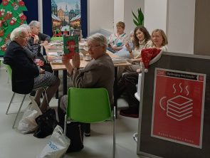 Uczestniczki siedzą przy stole, jedna z nich trzyma książkę "Pani March"
