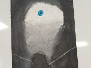 Zdjęcie przedstawia rysunek. Całe tło rysunku jest bardzo ciemne, niemal czarne. Na tym tle namalowany jest duży, jasny kształt przypominający oko.