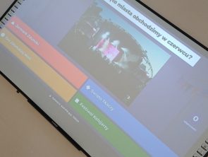 Zdjęcie pod kątem dużej tablicy interaktywnej wyświetlającej quiz z pytaniem „Jakie święto miasta obchodzimy w czerwcu?".