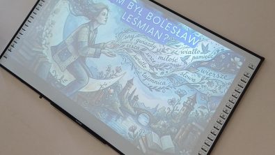 Zdjęcie przedstawia duży ekran interaktywny zawieszony na ścianie. Wyświetla on grafikę z pytaniem „KIM BYŁ BOLESŁAW LEŚMIAN?". Na ilustracji widać kobietę siedzącą na półksiężycu oraz wypisane wokół niej słowa związane z poezją, takie jak „sny", „miłość" czy „wiersze".